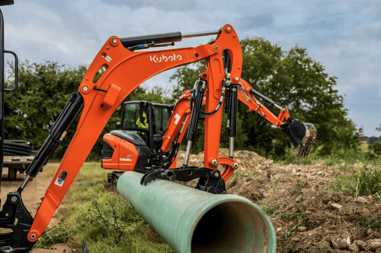 Compact Excavator picking up pipes